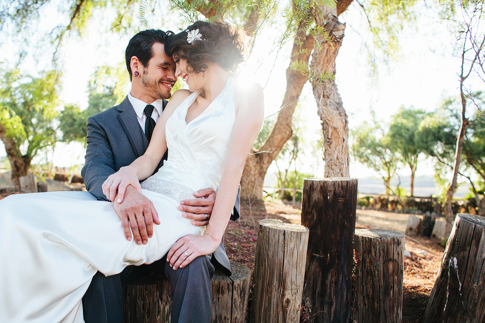 This is a photo of the bride and groom sitting on a little fence.