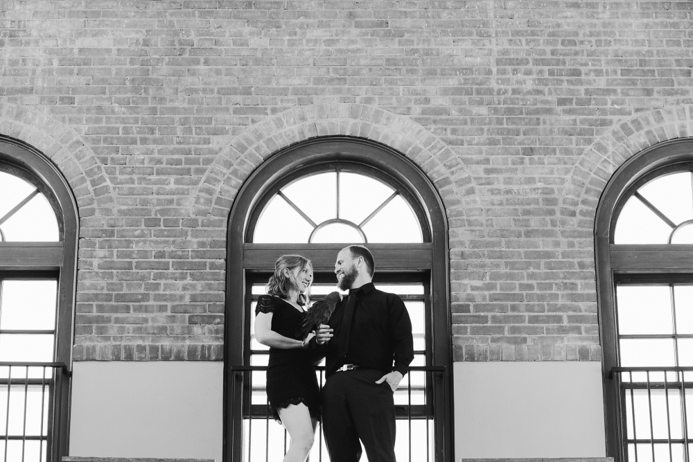 The couple and bird by a brick wall. 