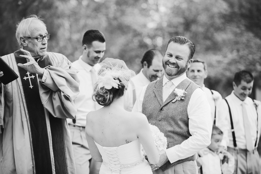 A black and white photo of the groom laughing during the ceremony. 