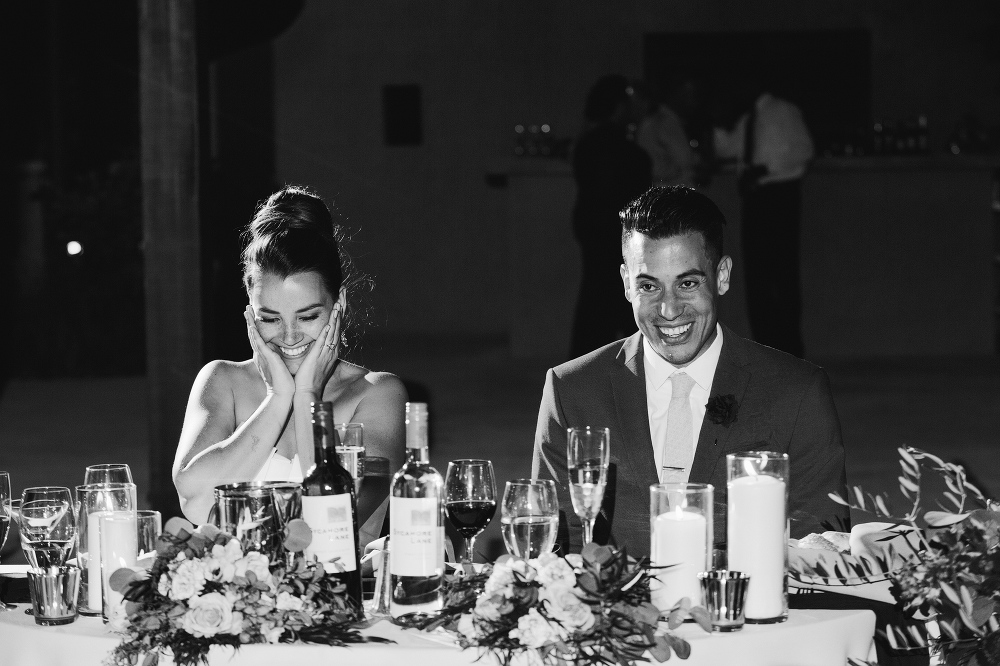 This is a photo of the bride and groom listening to the maid of honor toast. 