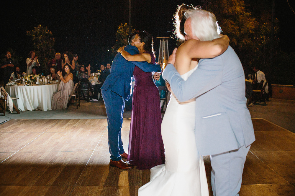 This is a sweet photo of the bride and groom hugging their mom and dad after parent dances. 
