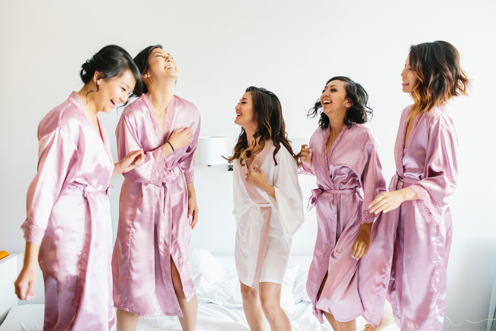 The bridesmaids and bride jumping on the bed. 