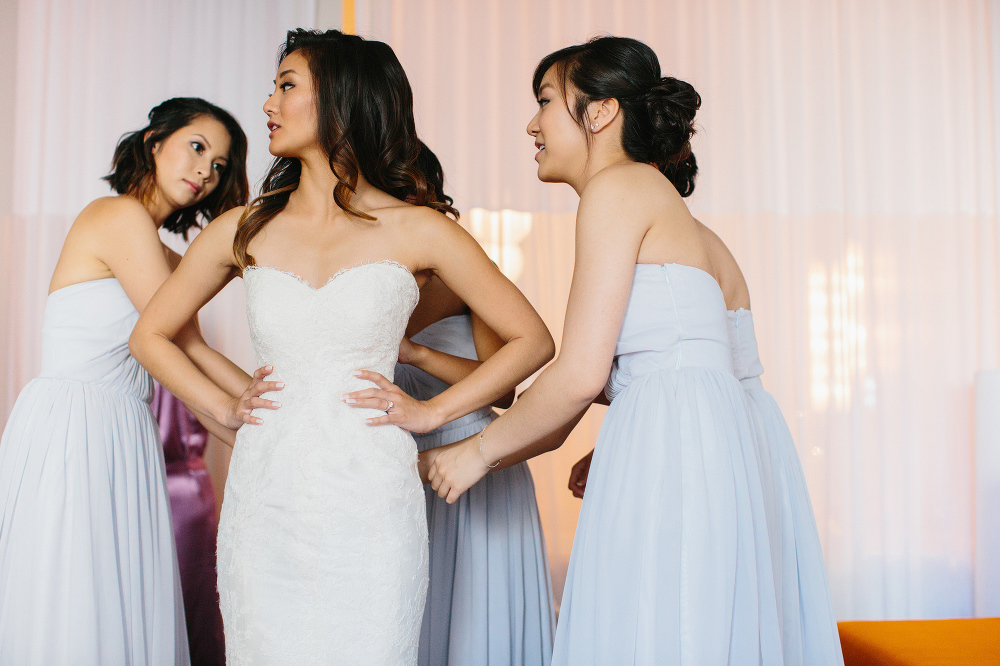 The bridesmaids helped Annalisa get in her wedding dress. 