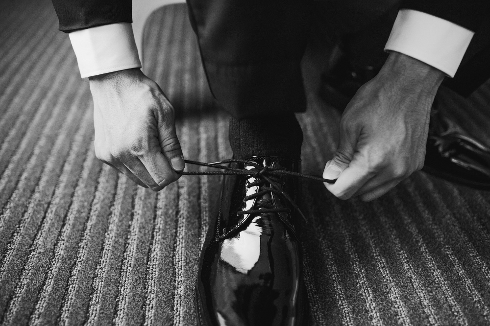 Will is tying his black shoes on his wedding day. 