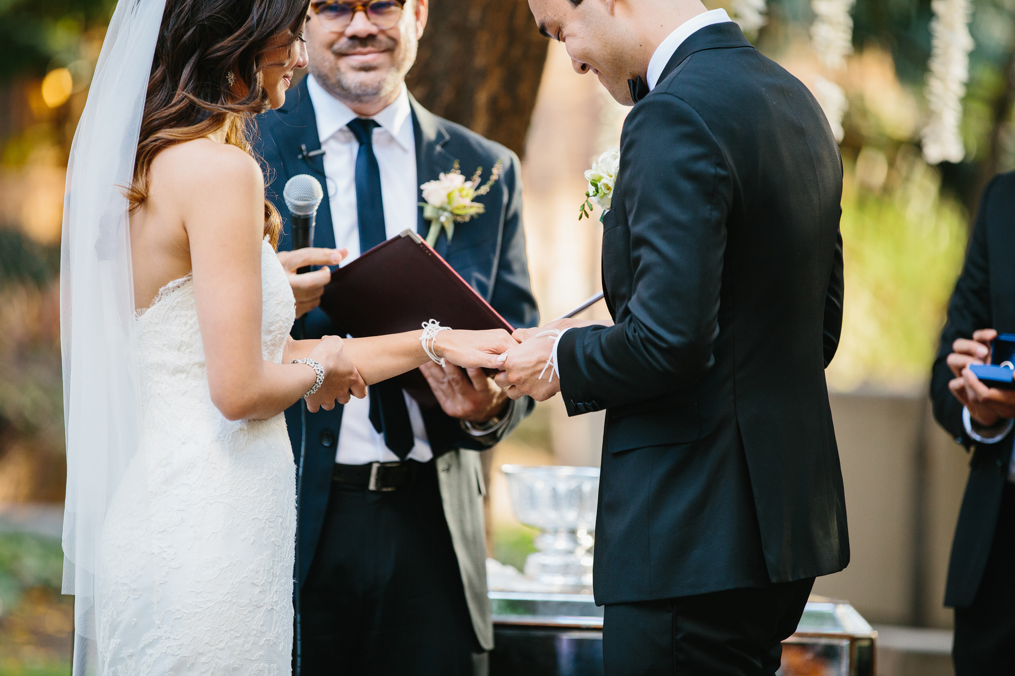 The groom putting on the bride's wedding ring. 