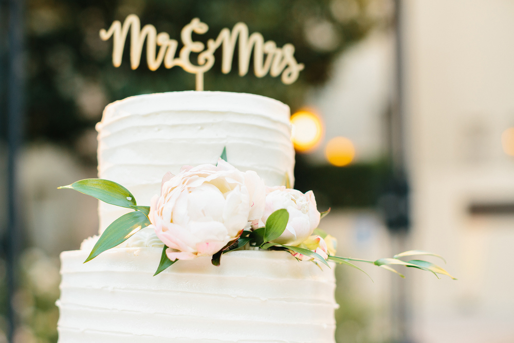 A photo of the wedding cake with a Mr. and Mrs. cake topper. 
