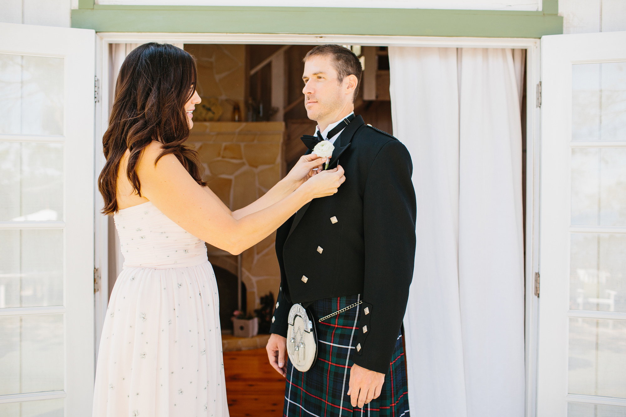 A bridesmaid pinning the groom's boutonniere. 
