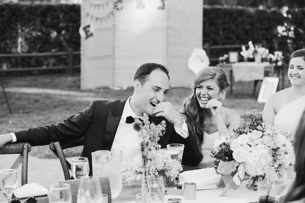 The bride and groom laughing during toasts. 