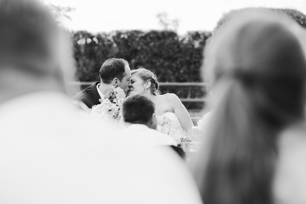 The bride and groom kissing during dinner. 