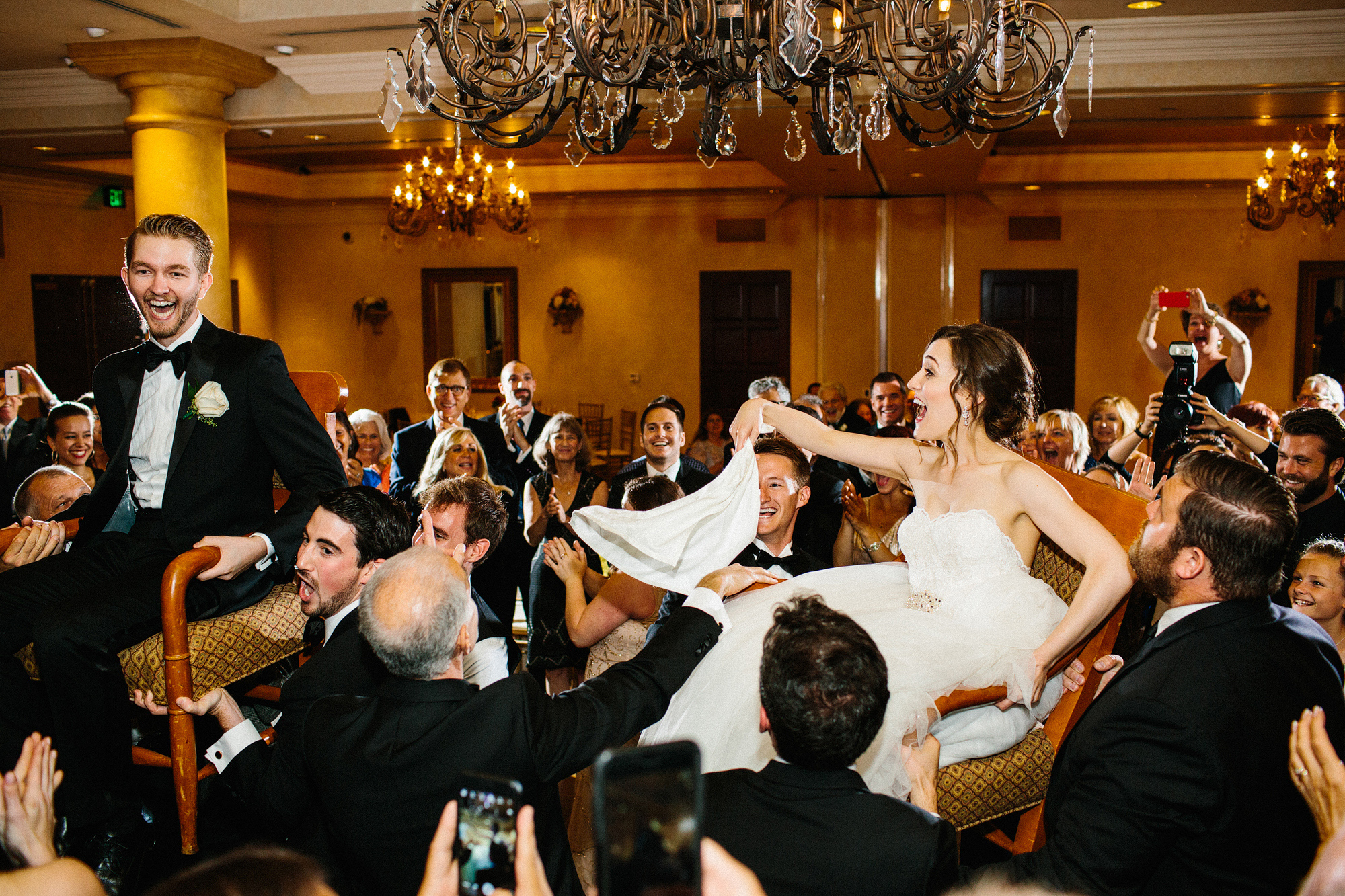 The bride and groom being lifted on chairs. 