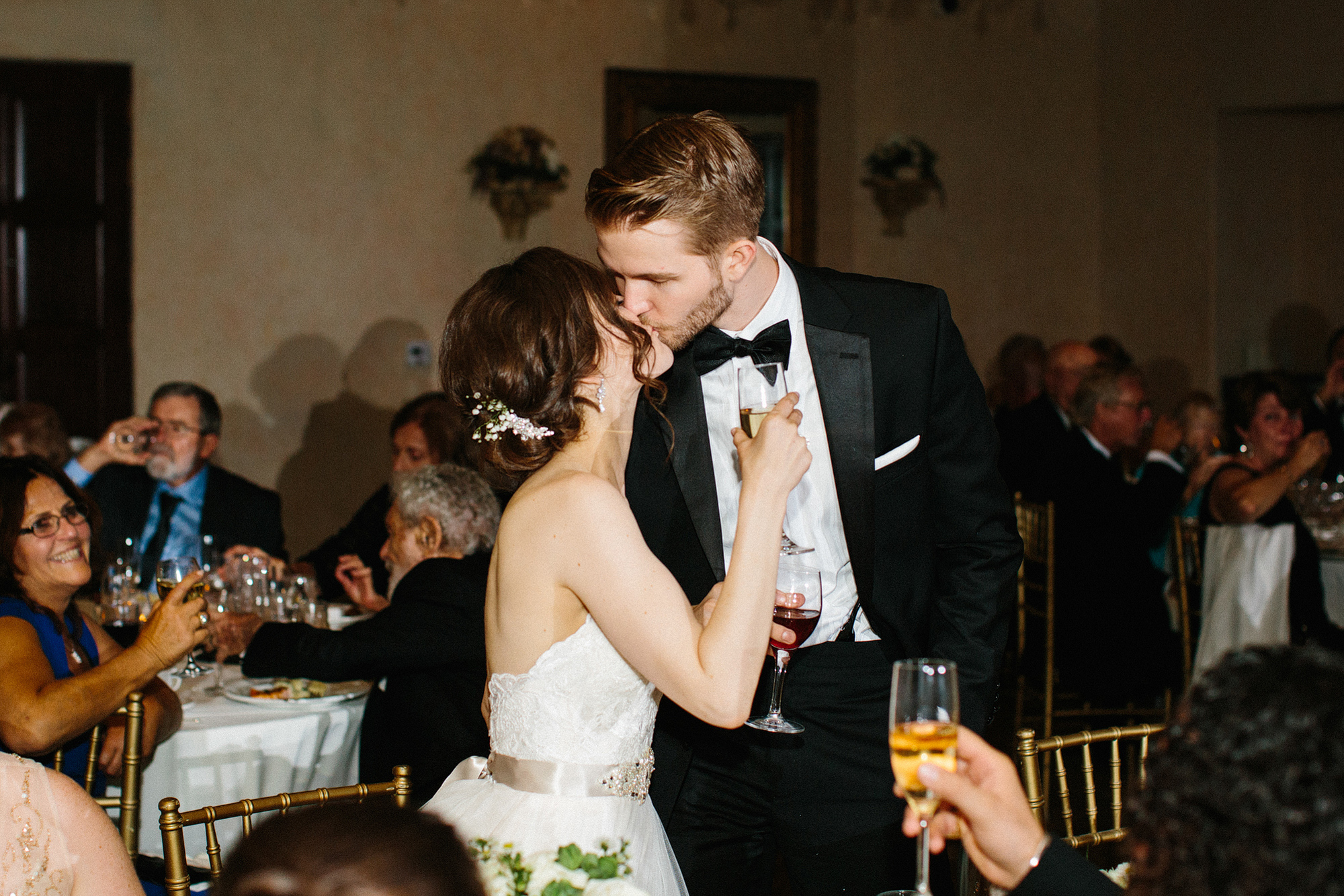 The bride and groom kissing during toasts. 