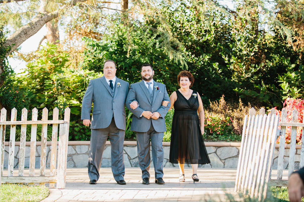 The groom walking down the aisle with his parents. 