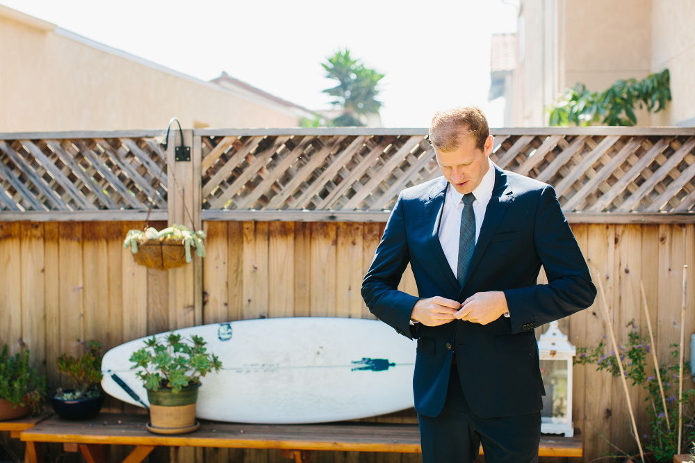 The groom putting on his suit jacket. 