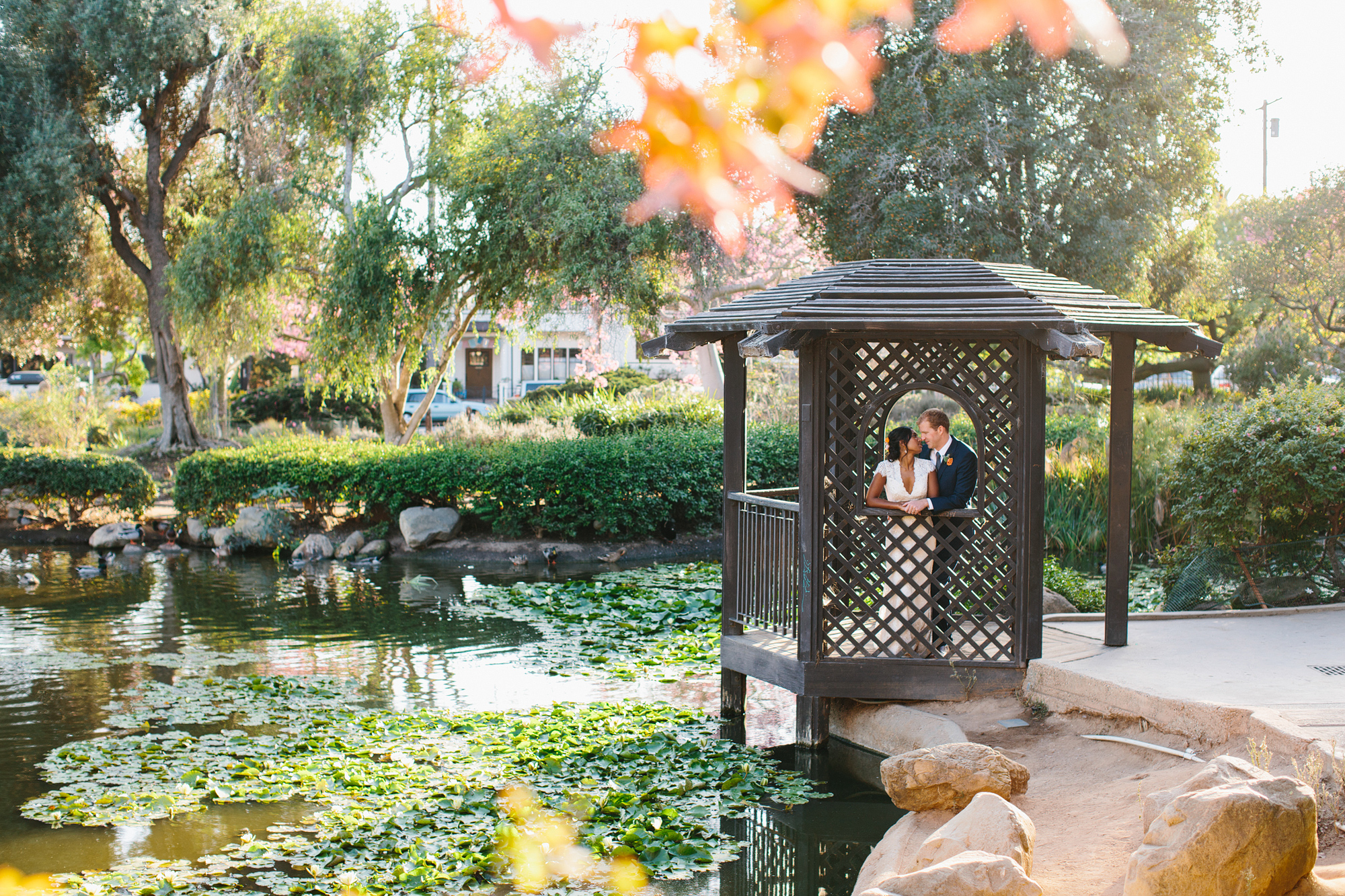 The bride and groom in a gazebo next to a lake. 