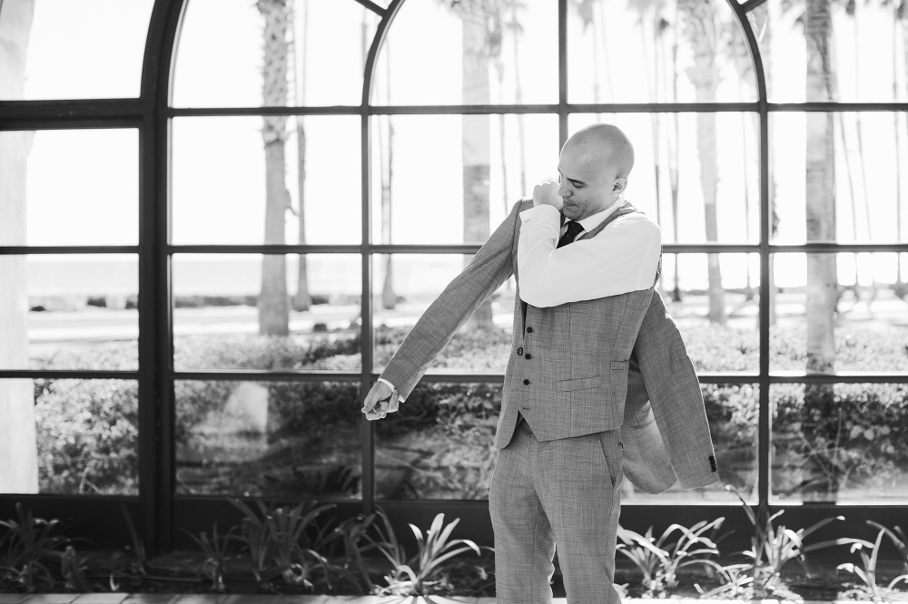 The groom putting on his suit jacket. 