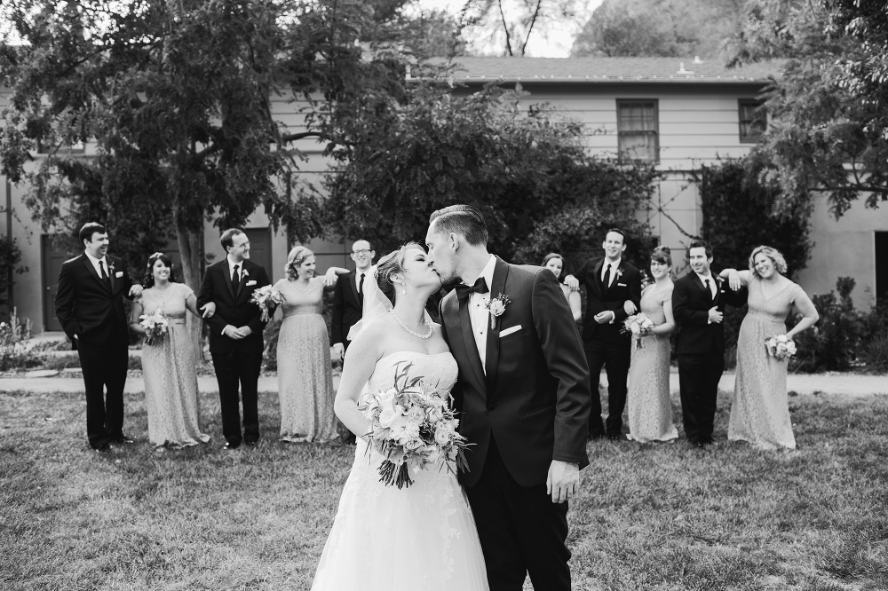 A cute photo of the couple kissing with the bridal party in the background. 