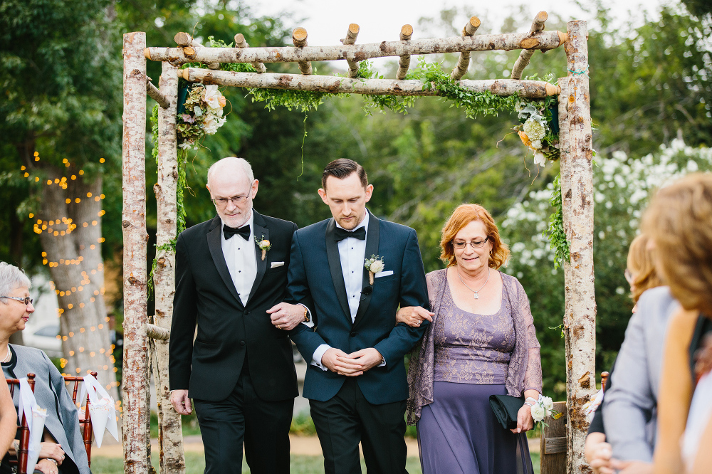 The groom walked down the aisle with both of his parents. 