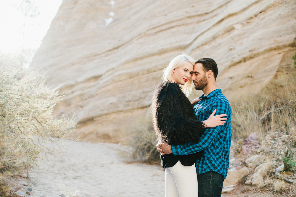 The couple standing near a large rock. 