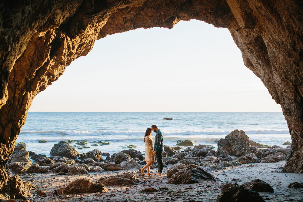 The couple standing in a beach cave. 