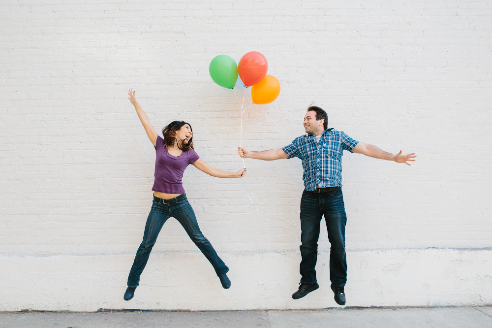 Janice and Mike jumping while holding the balloons. 