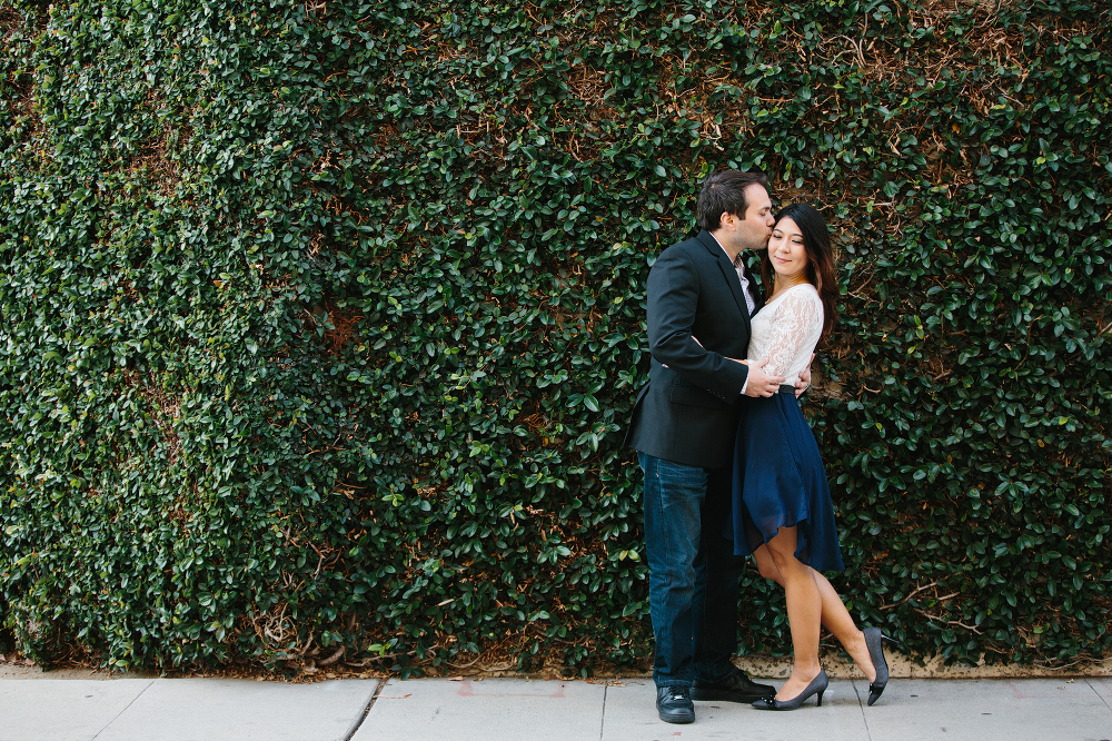 A beautiful wide shot of the couple in front of the vine wall. 