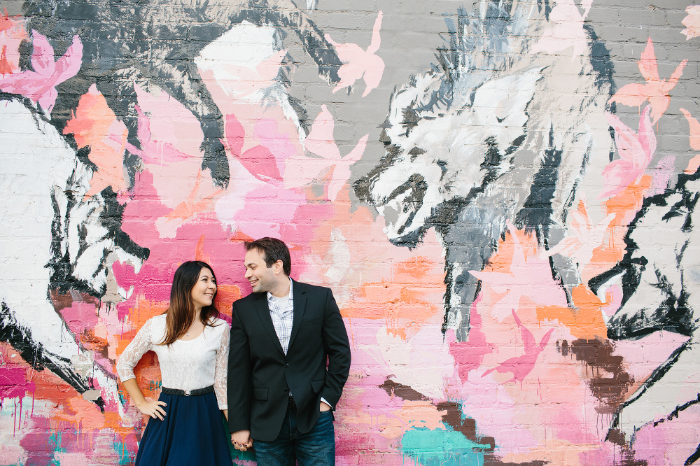 Janice and Mike looking at each other in front of a wall mural. 