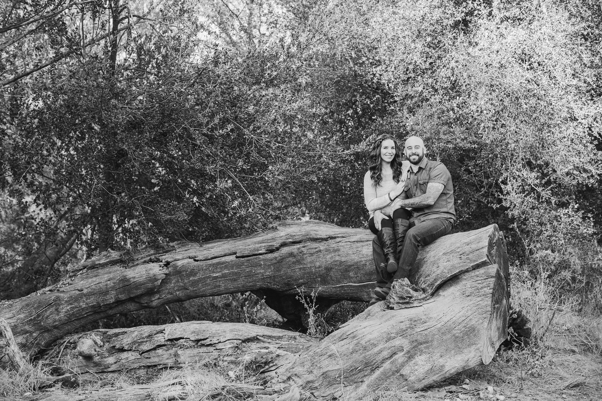 Shara and Steven sitting on a fallen tree. 