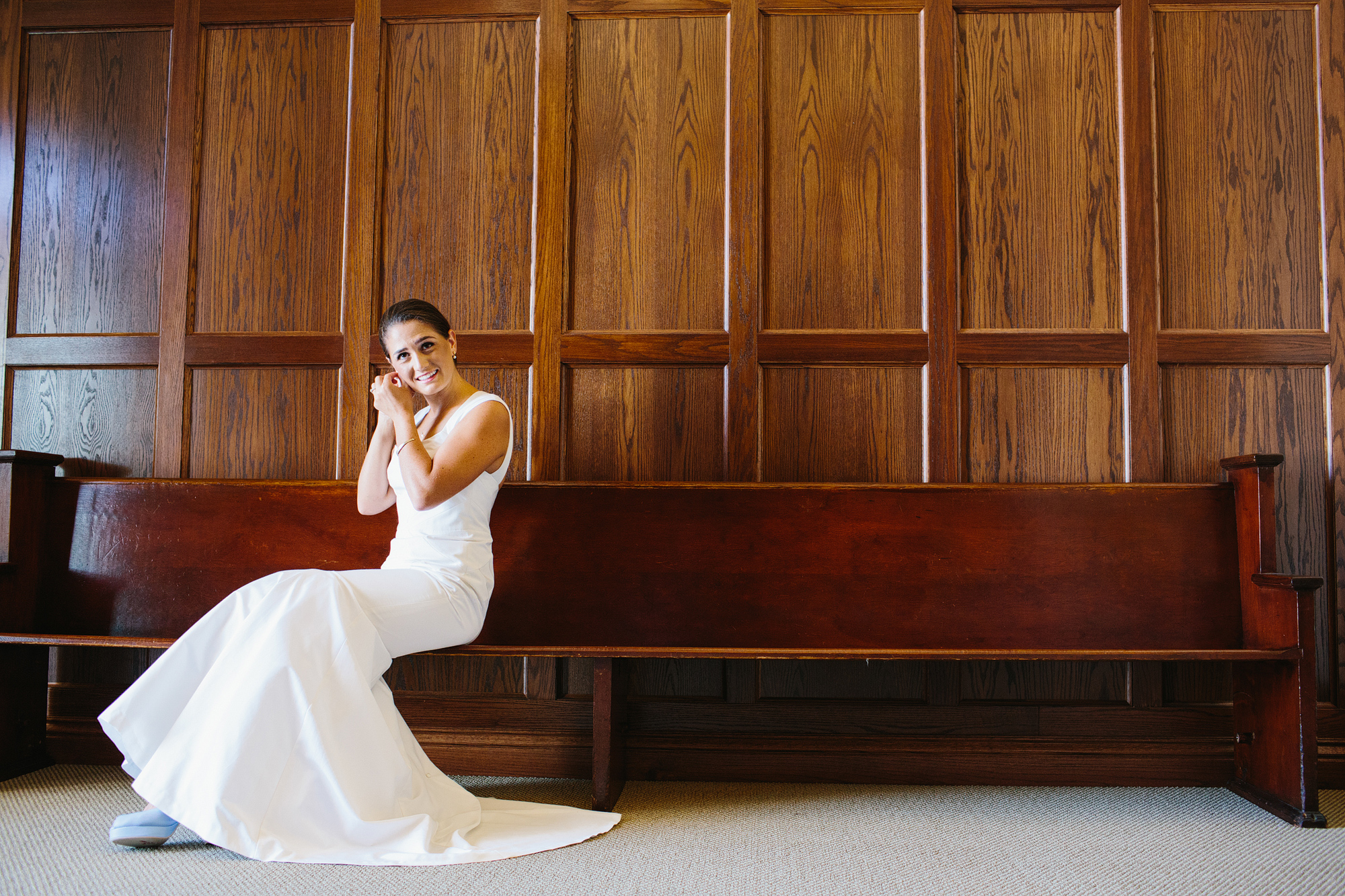 A photo of the bride sitting on a pew. 