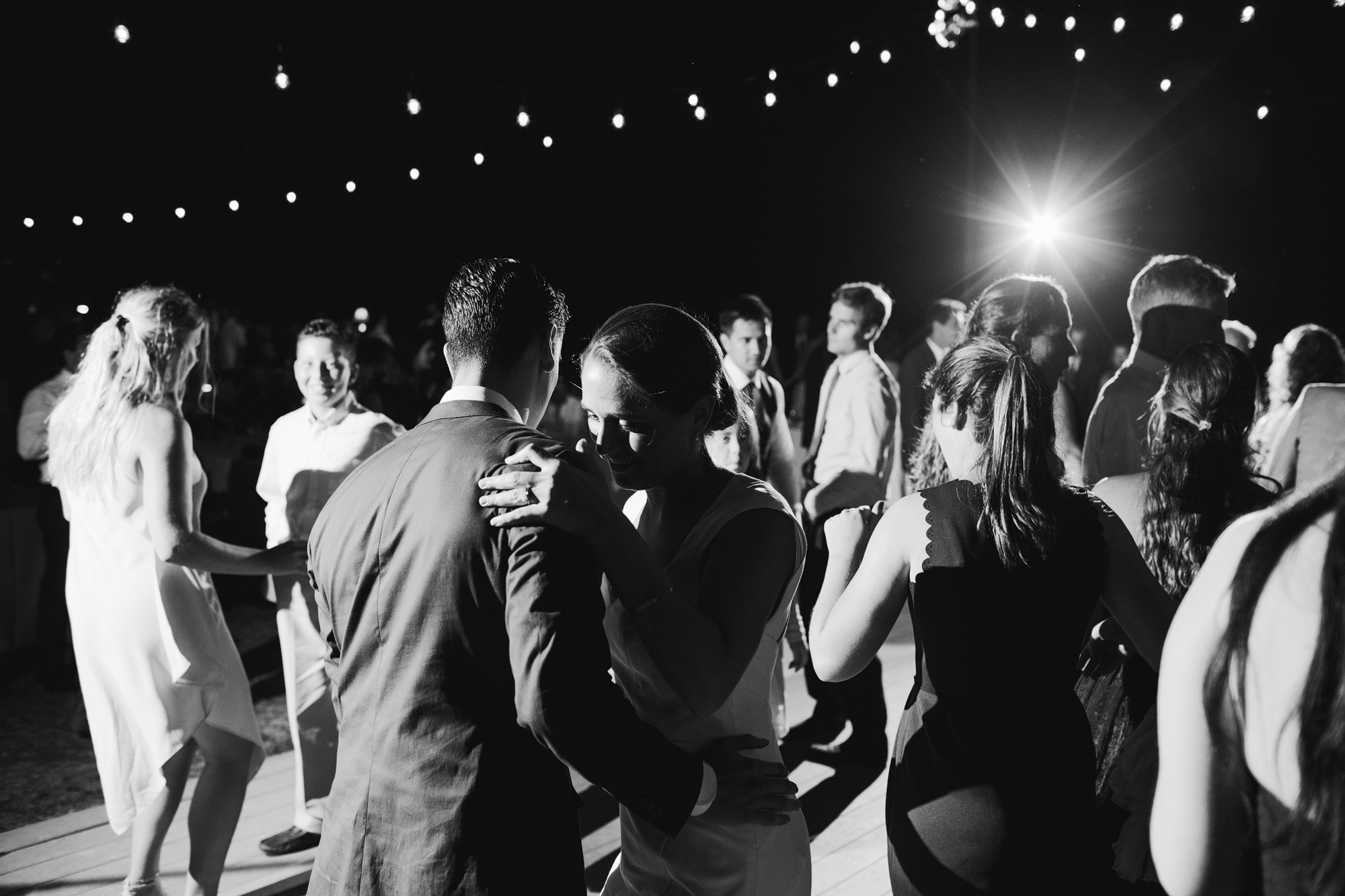 A black and white photo of guests and the couple dancing. 