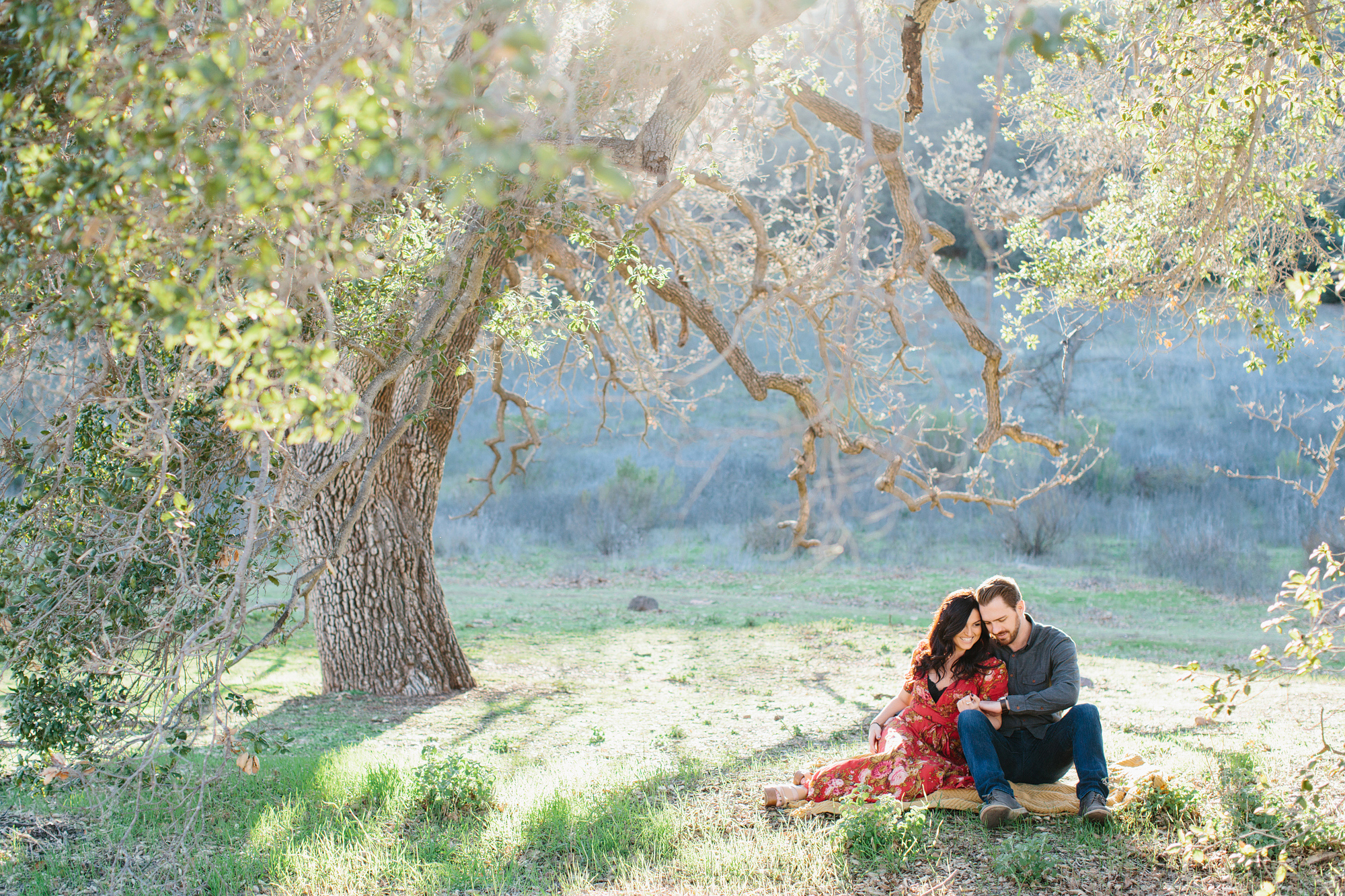 Niky and John sitting under a large tree. 