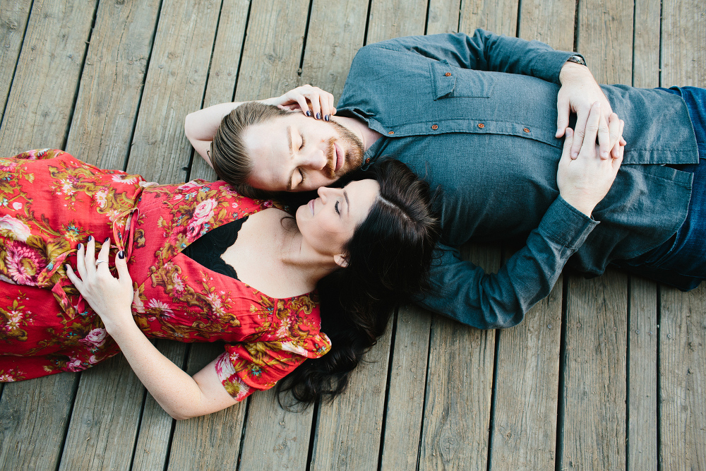 The couple laying on a wood floor. 