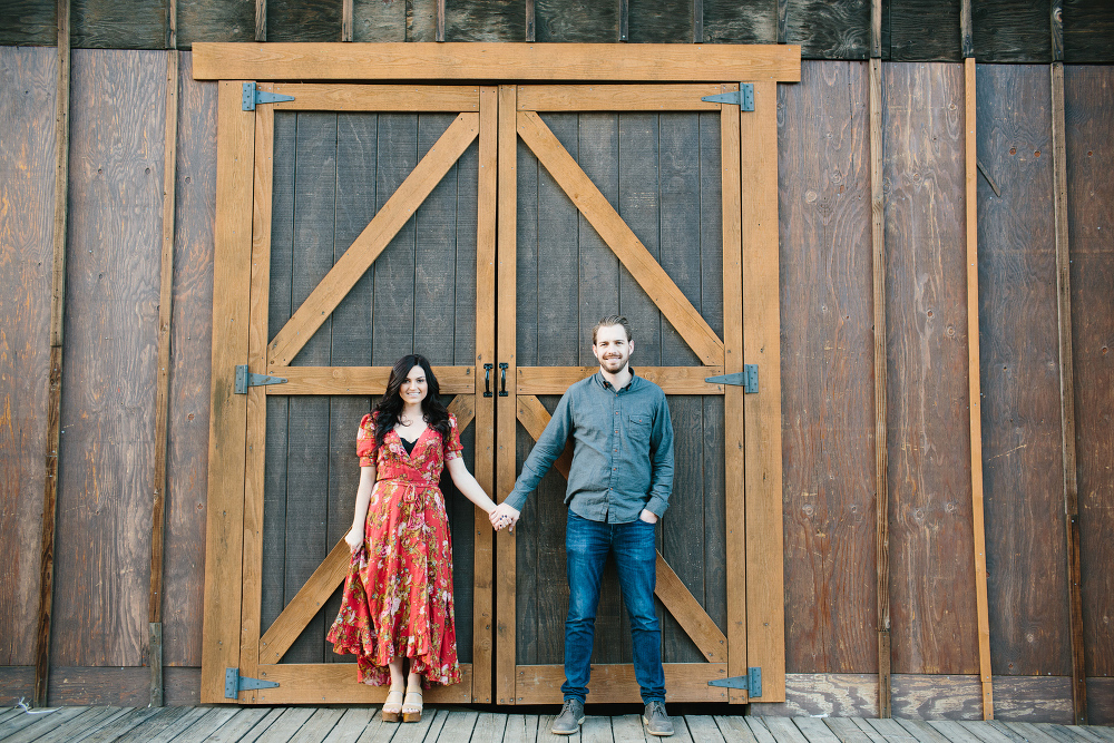 The couple standing in front of a large barn. 