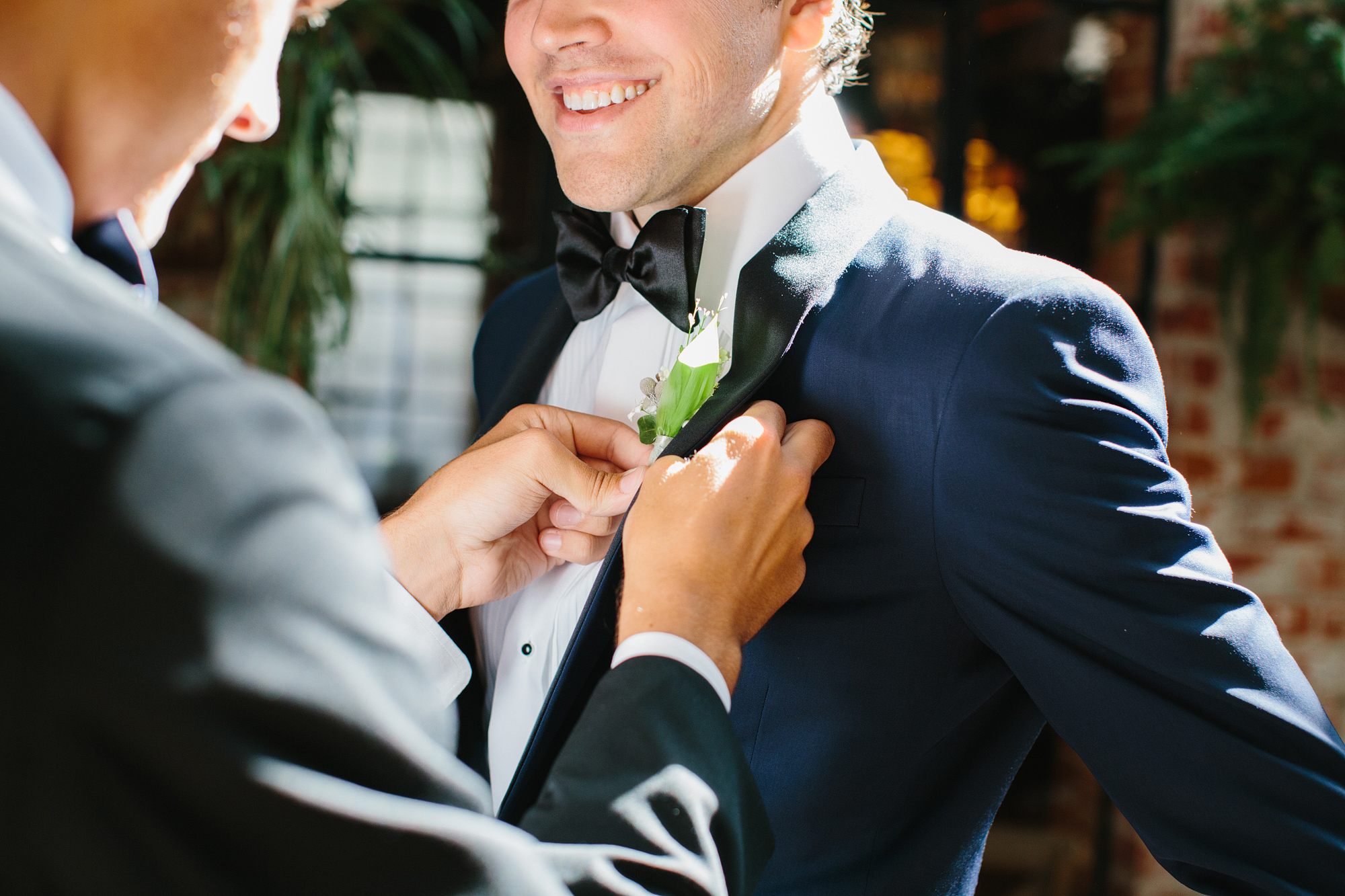 A groomsmen pinning the groom's boutonniere. 