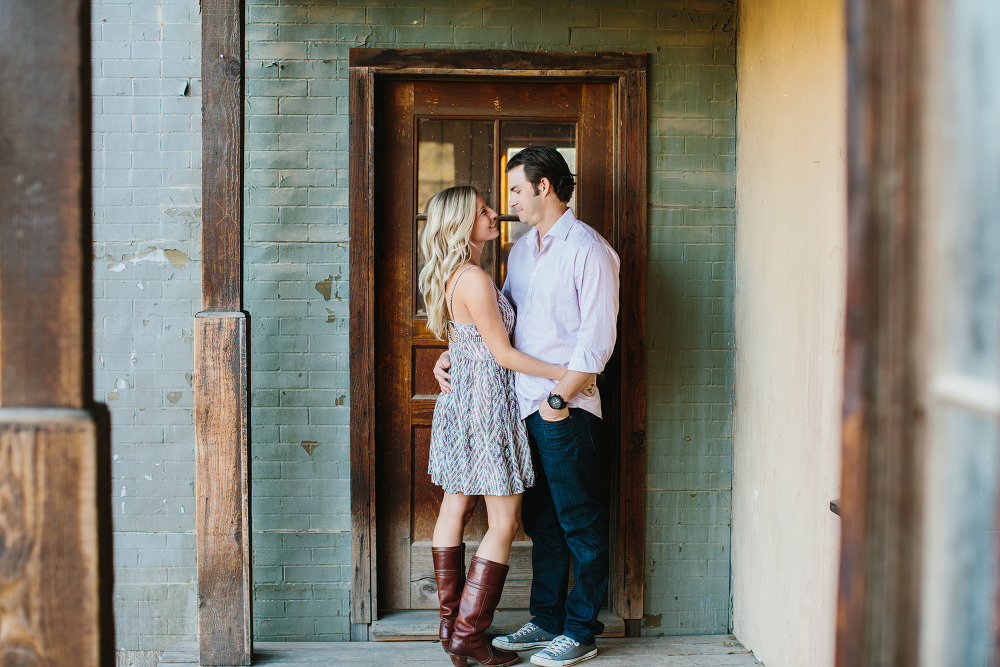 Megan and Travis leaning on a wood door. 