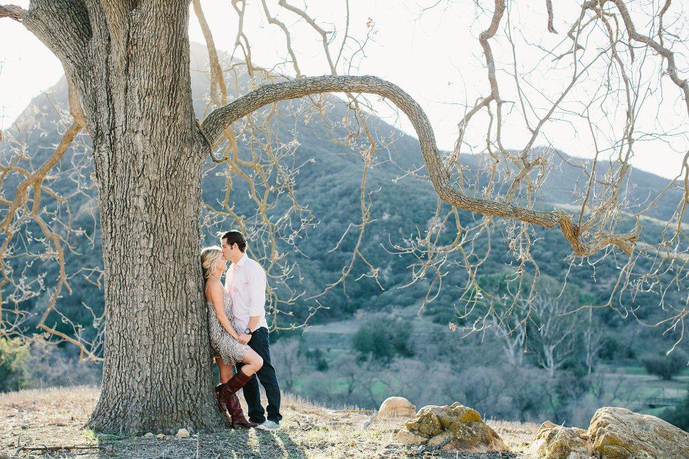 The couple leaning on a tree. 