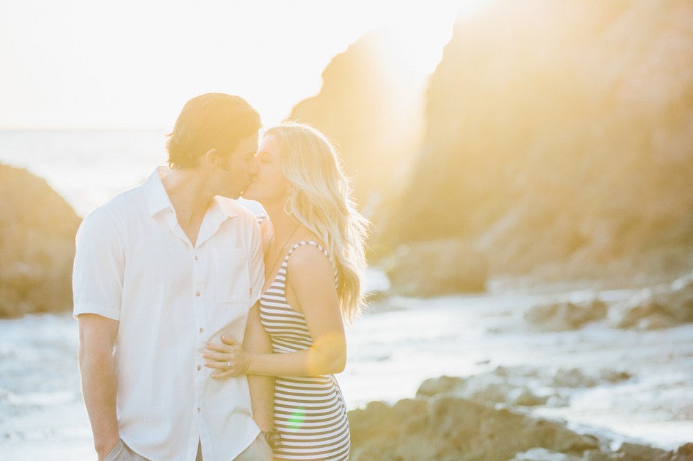 A bright sun filled photo of the couple kissing. 