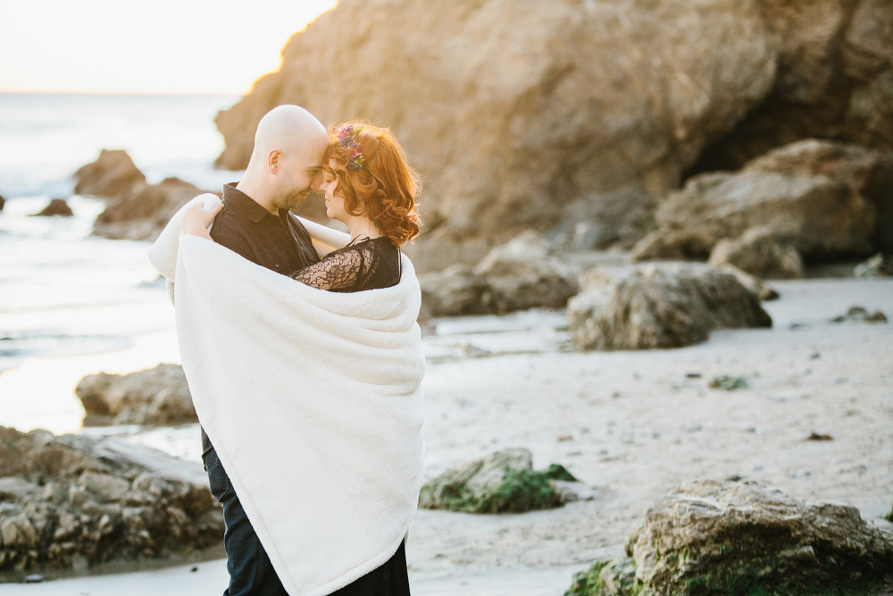 The couple wrapped in a blanket at sunset. 