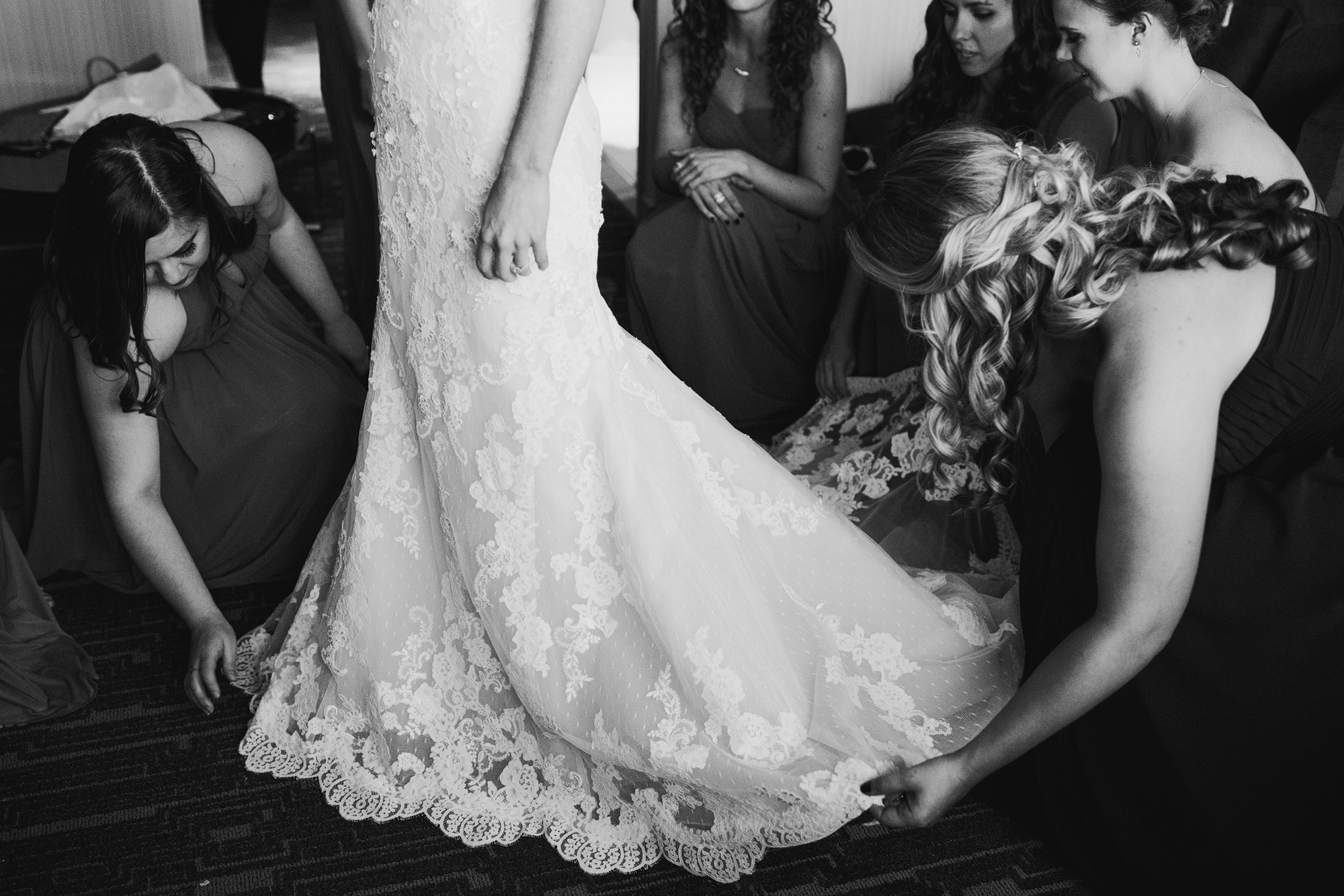 The bridesmaids fixing Ashley's dress. 