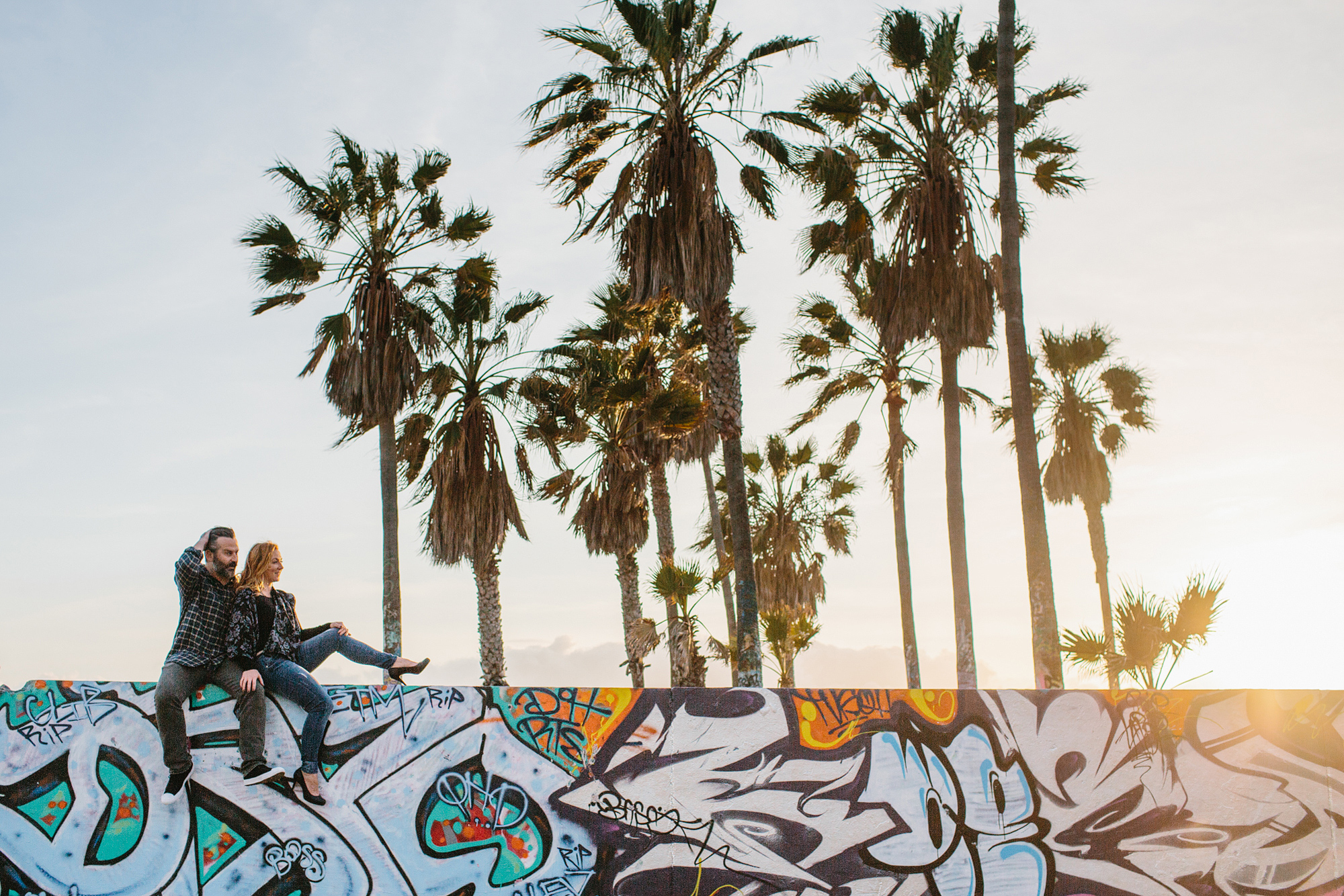 The couple sitting on a wall at the beach. 